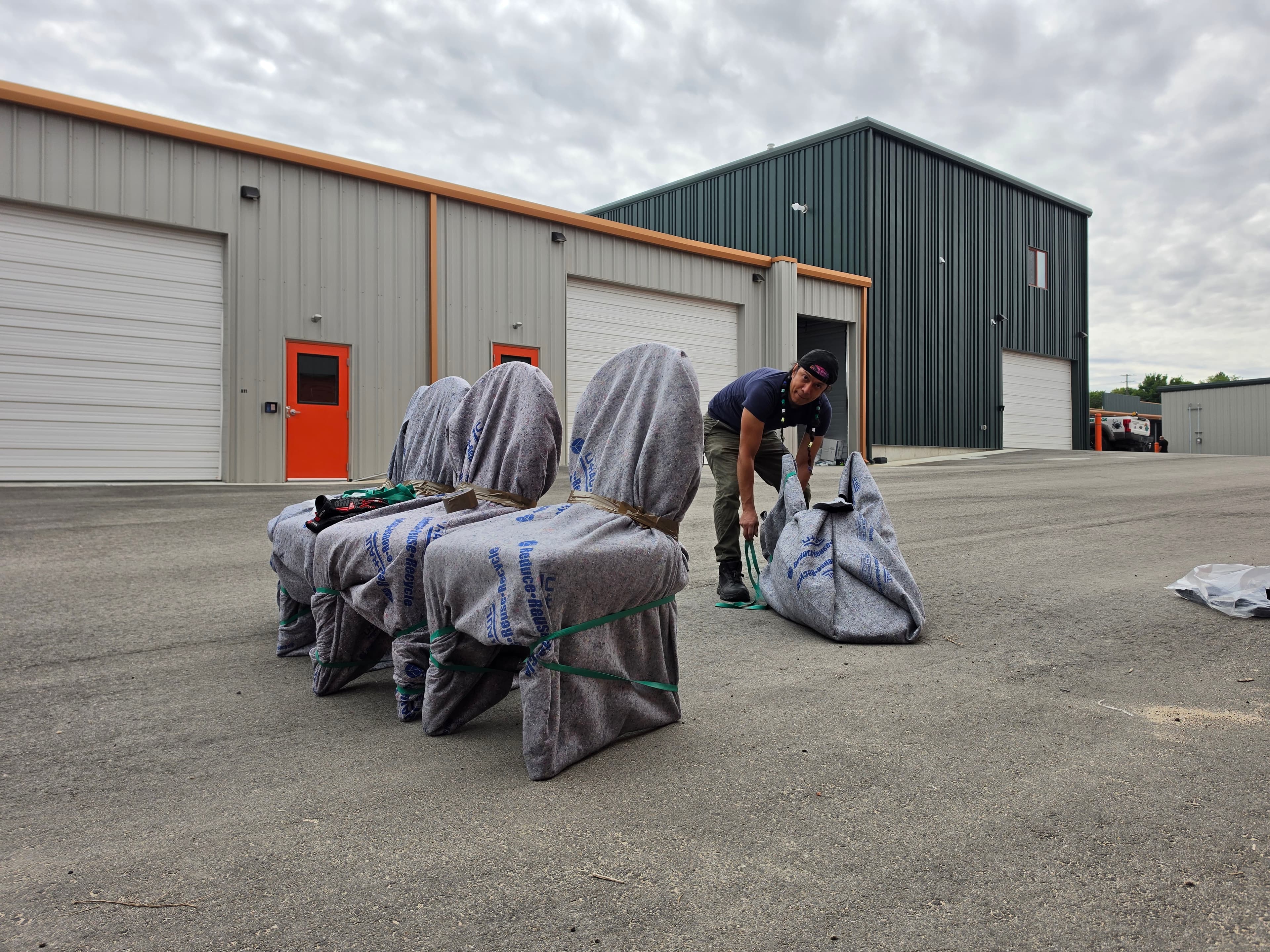 We Load crew member on a job at a storage facility, blanket-wrapped chairs lined up