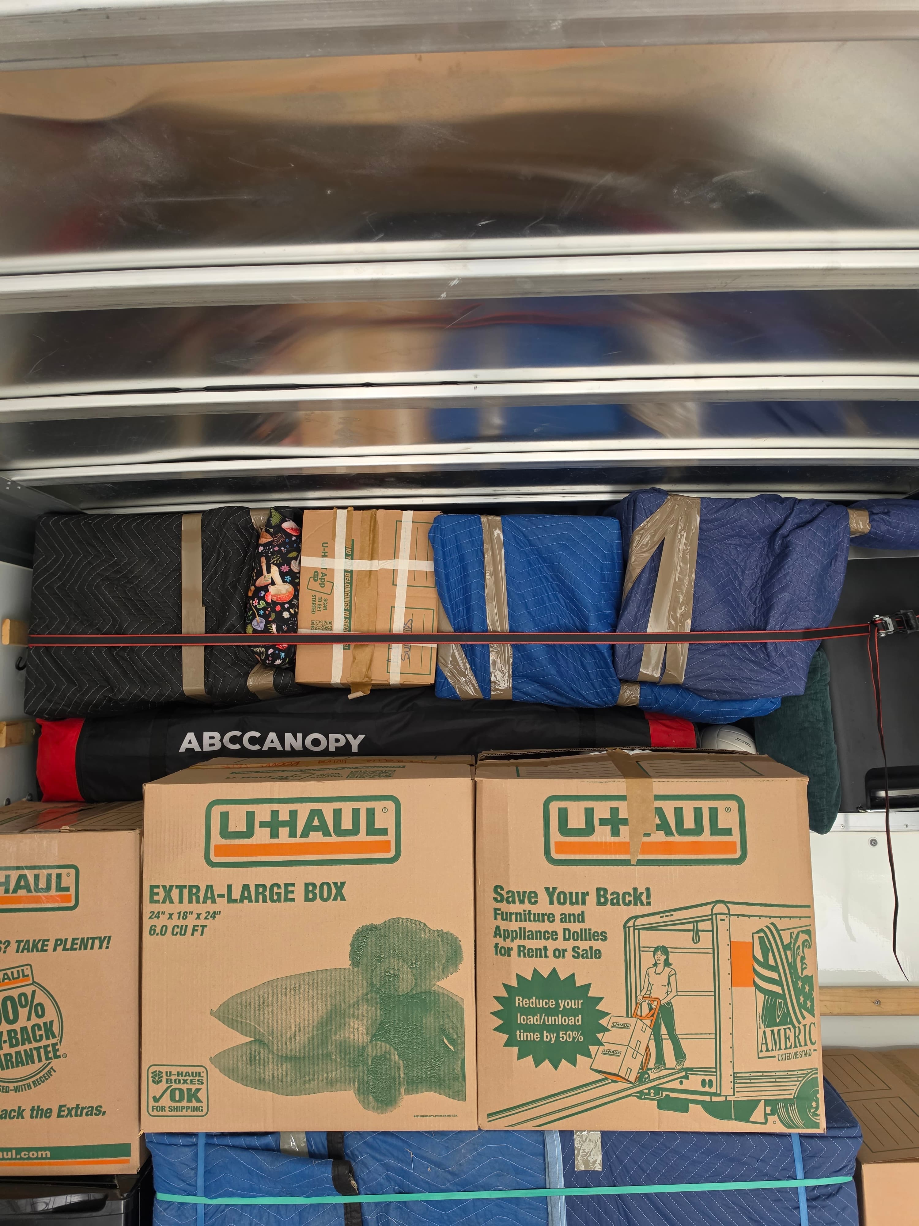 Mid-load: blanket-wrapped furniture strapped down tight.